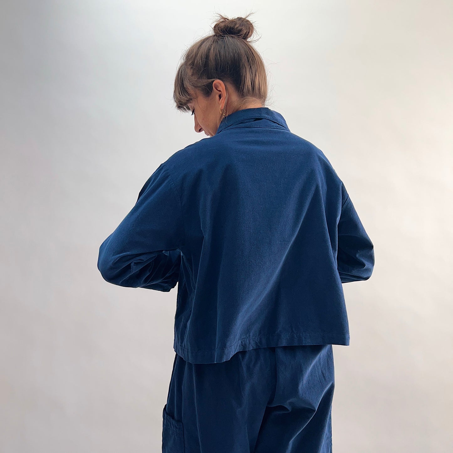 Back view of the Bryn Walker Corduroy Audrey Jacket in Nova, showing cropped hemline, relaxed silhouette, and navy pinwheel corduroy texture