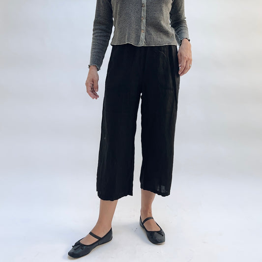 Cut Loose Hanky Linen Easy Crop Flood Pant in Black, black linen wide-leg crop pant with hands at sides, styled with a grey button-front cardigan and black Mary Jane flats — straight-on front view showing mid-calf flood length