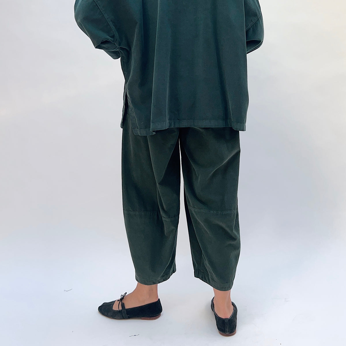 Eleven Stitch Corduroy Three Pocket Pant in Konbu, back view showing the elastic waistband and barrel crop leg in dark green fine-wale corduroy
