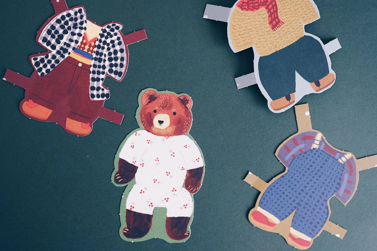 Small Adventure Bear Paper Doll Cozy Holiday Card, pop-out bear in floral pajamas surrounded by three paper outfits with folding tabs.