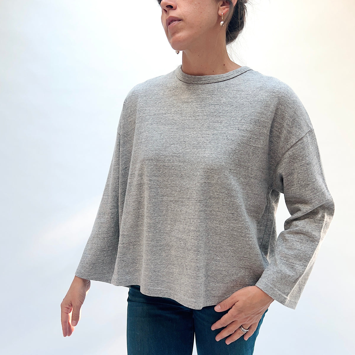 Closer front view of the grey cotton knit pullover, showing the heathered fabric and round neckline.