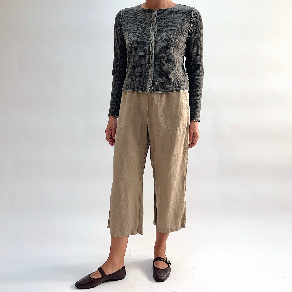 Cut Loose Hanky Linen Easy Crop Flood Pant in Suede, sandy tan linen wide-leg crop pant styled with a grey button-front cardigan and brown Mary Jane flats — full-length front view showing silhouette and proportions