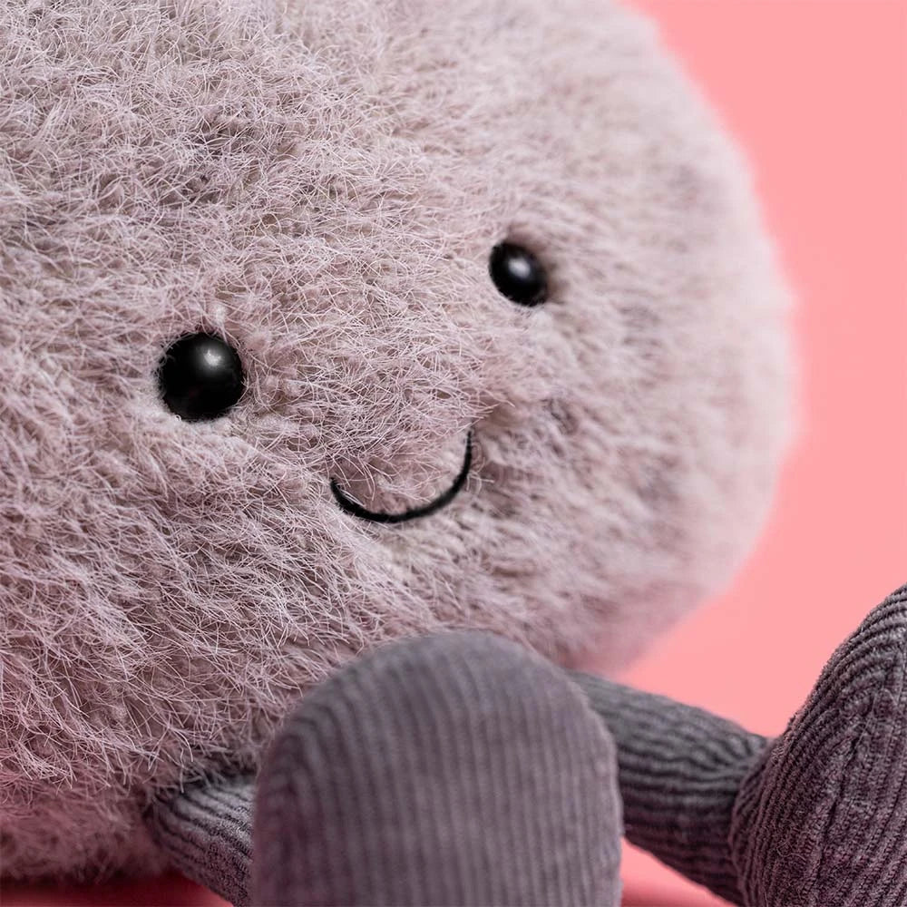 Plush toy resembling a round grey stone with a smiling face and grey legs on a pink background