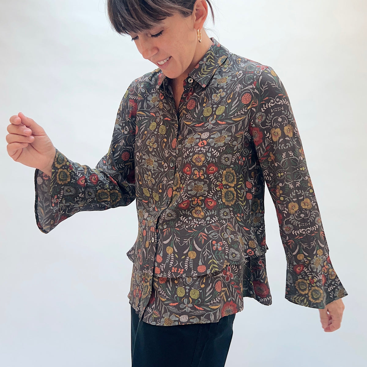 Habitat Crepe Garden Flounce Shirt in Olive, front three-quarter view showing the flounce bell sleeves, flounced hem, and garden floral print in motion