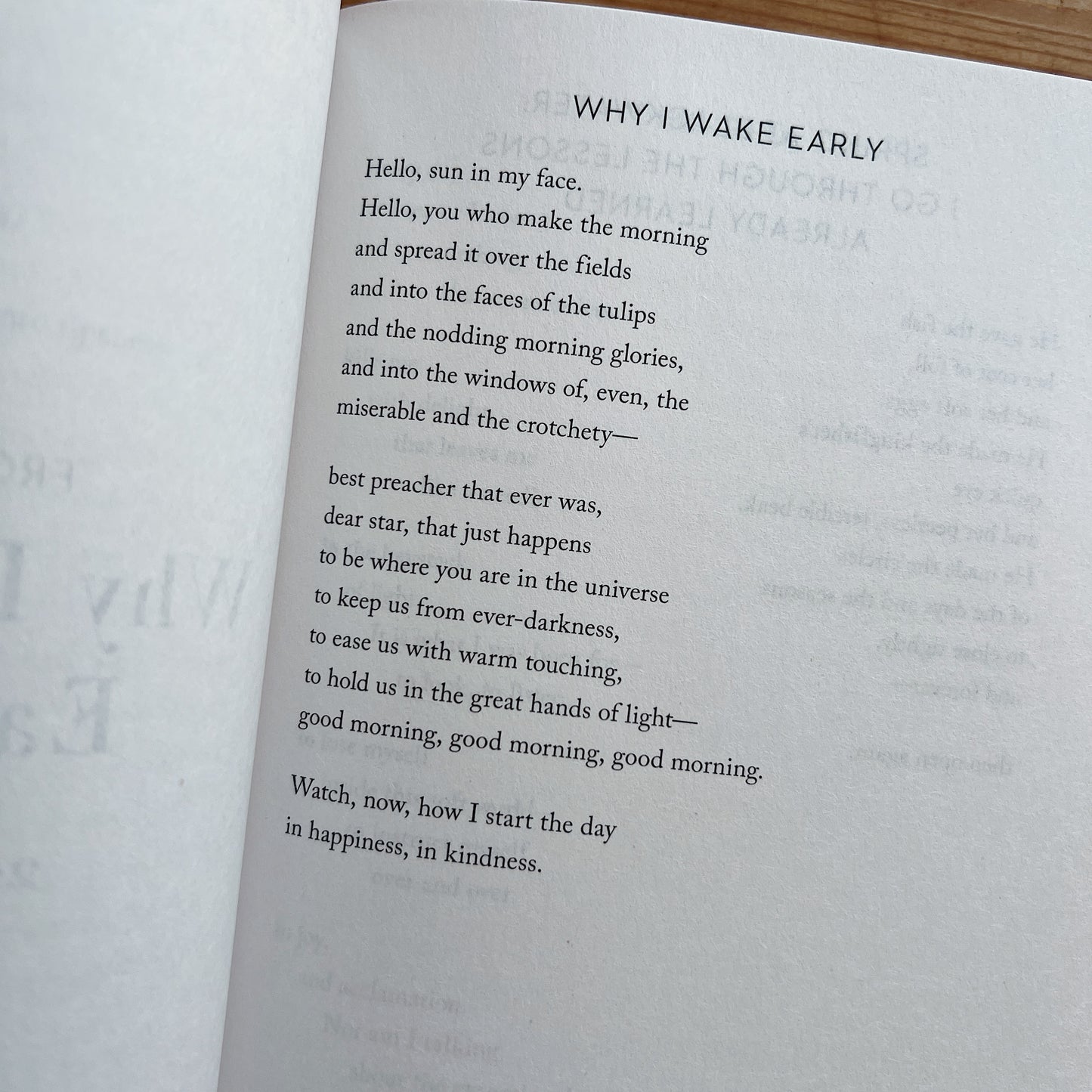Interior page of Devotions by Mary Oliver showing the full text of the poem "Why I Wake Early", open book photographed on wooden surface
