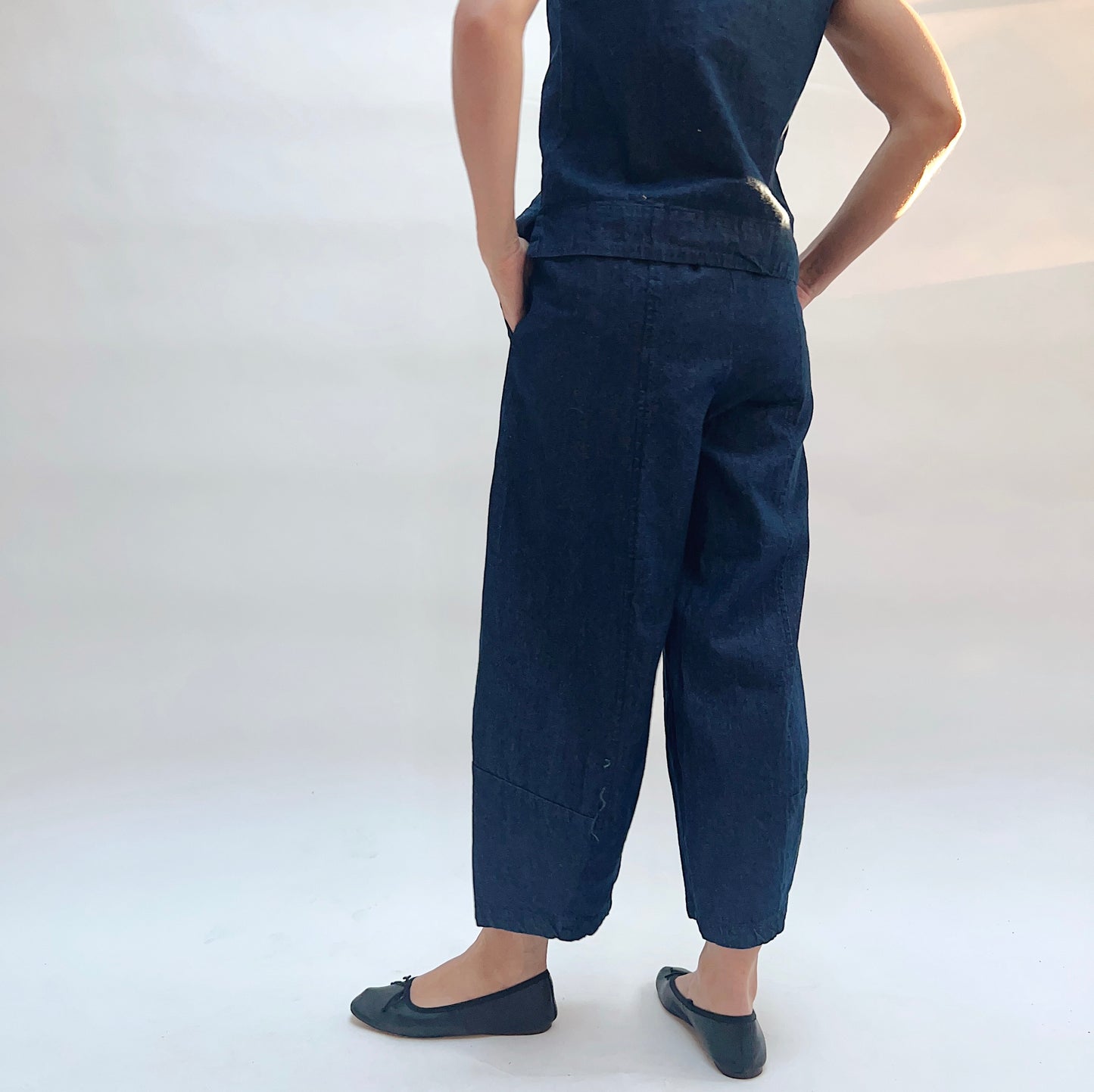 Person wearing navy blue top, pants and shoes on a white background