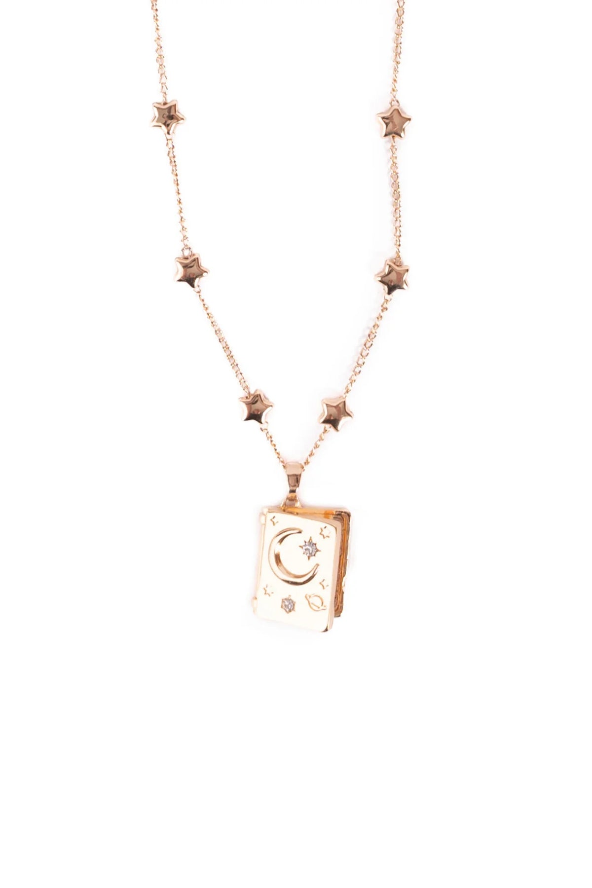 Close-up of the Great Pretenders It Must Be in the Stars Locket pendant, showing the book-shaped rose gold locket with crescent moon, star, and crystal engravings on the front, on a white background