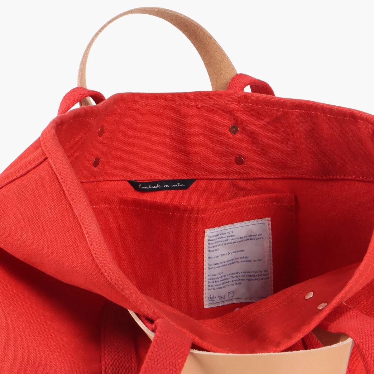 Interior of the Persimmon tote showing the inside pocket, care label, and handle attachments.