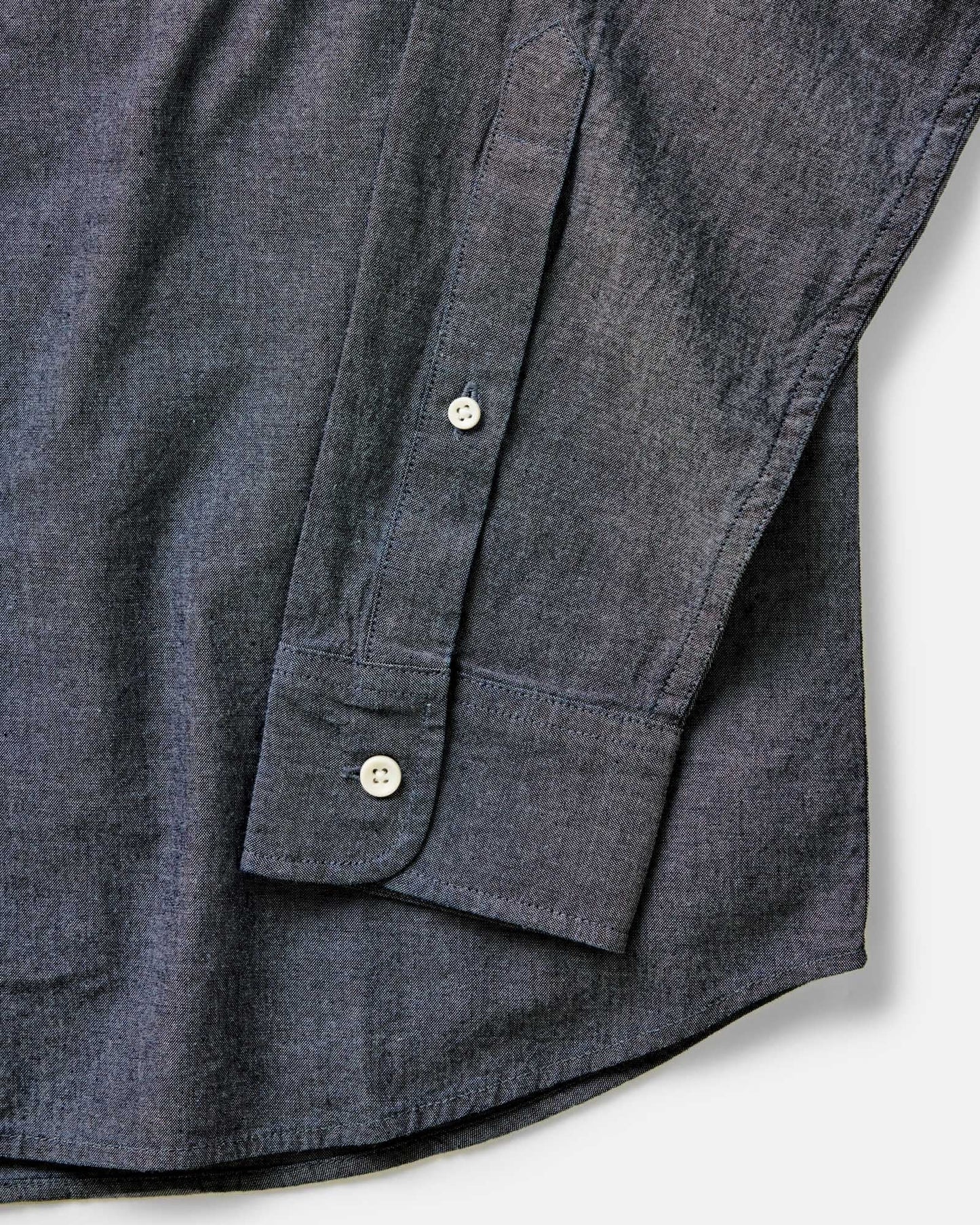 Close-up detail of The Jack in Rinsed Indigo Chambray showing barrel cuff, natural buttons, and double-needle felled construction on a white background