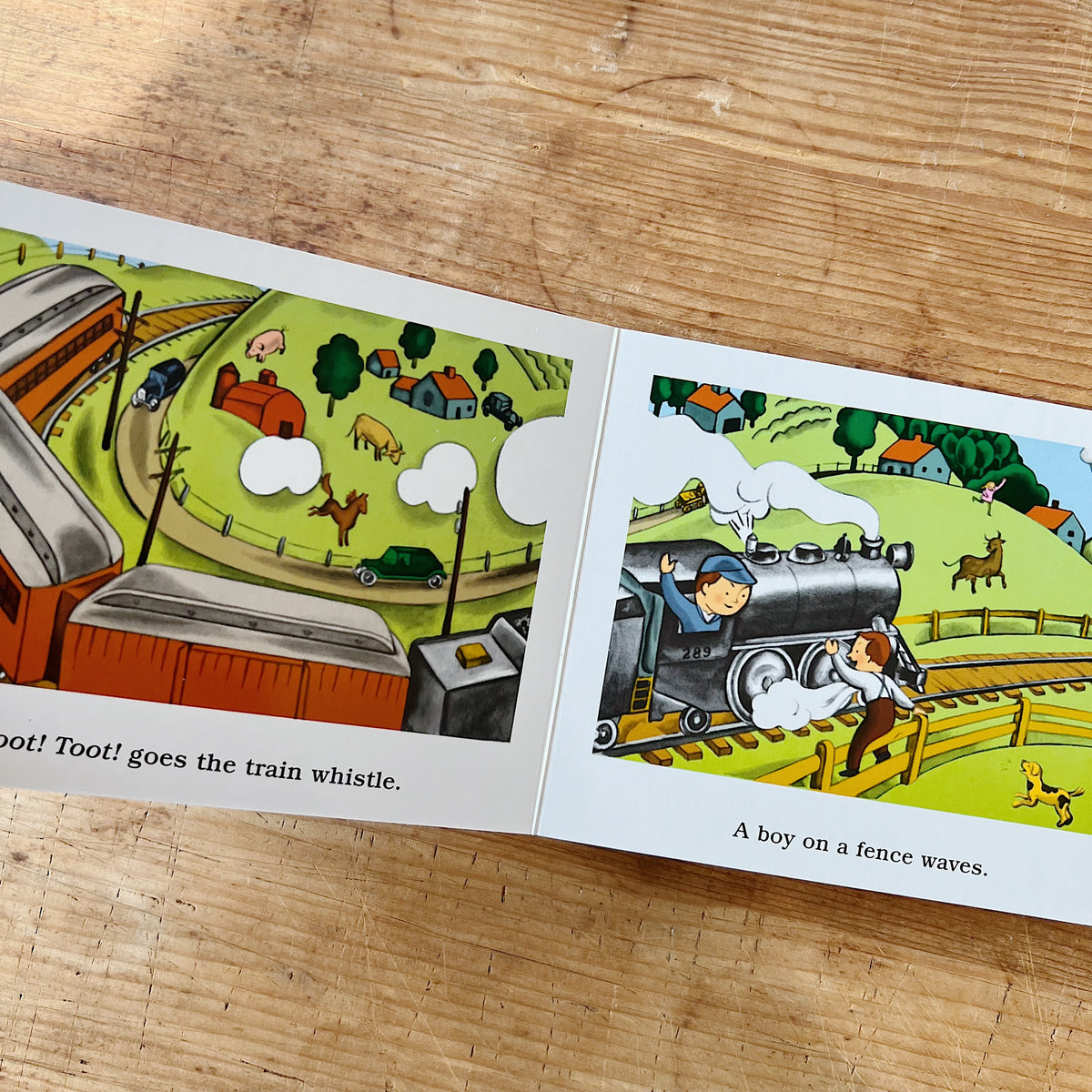 Interior spread of The Little Train showing Engineer Small waving from his steam locomotive as it passes a green countryside with farms and animals, beside text reading "Toot! Toot! goes the train whistle" and "A boy on a fence waves"
