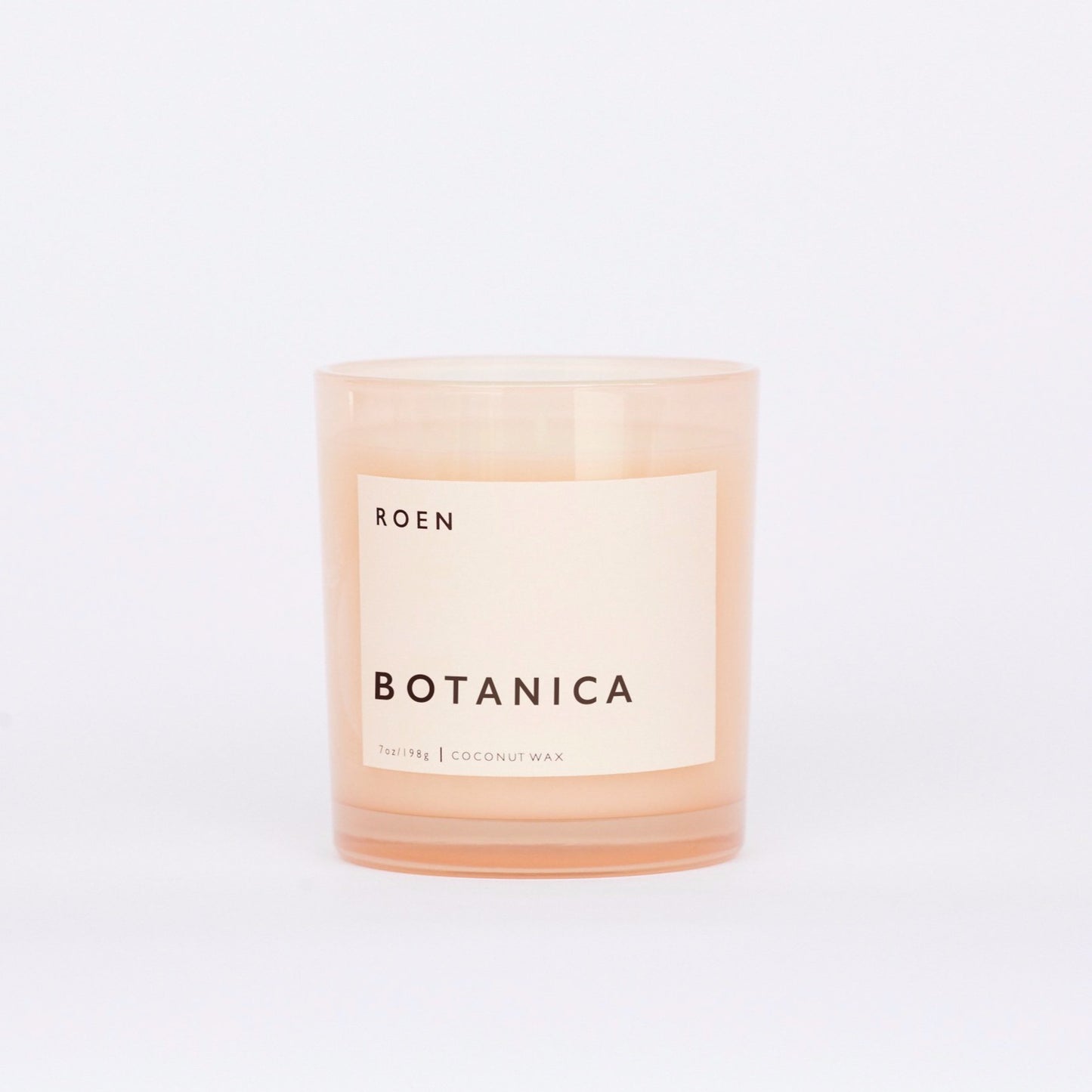 Front facing shot of Roen's Botanica scented candle in a pink glass jar with a light pink label and black font reading "Botanica".