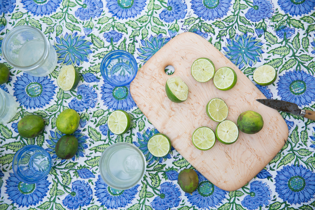 Ed Wohl cutting board holding limes on blue and green floral tablecloth