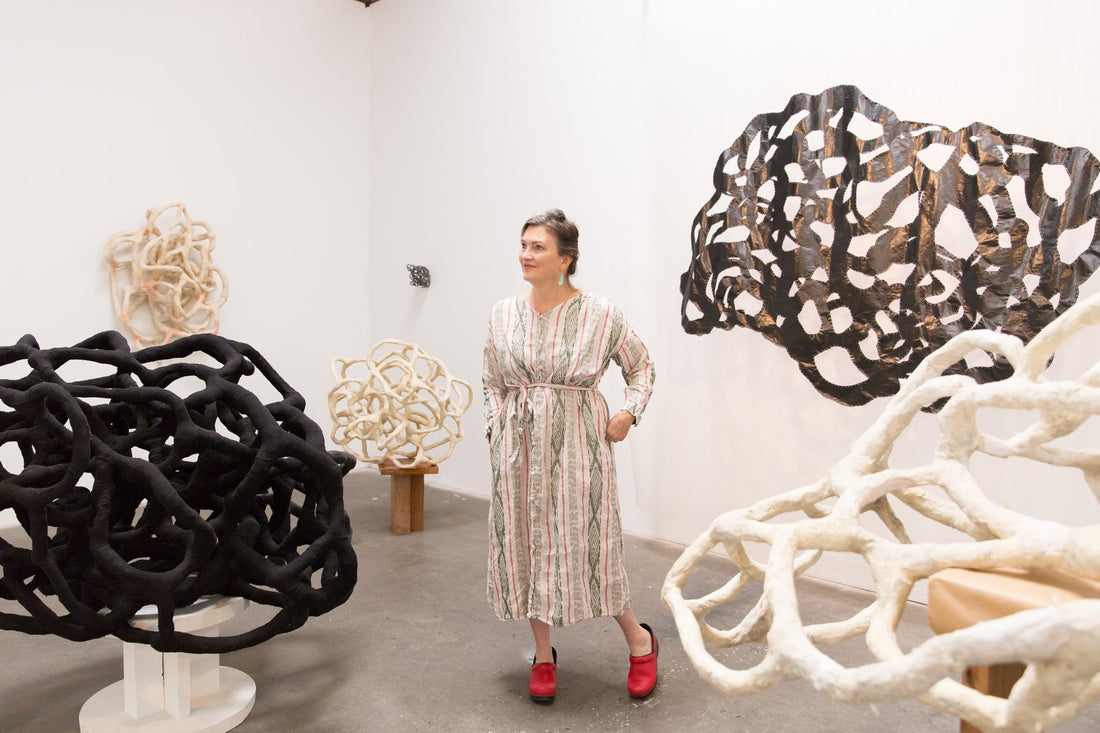 artist, Laura Cooper, surrounded by her sculptures in art studio 