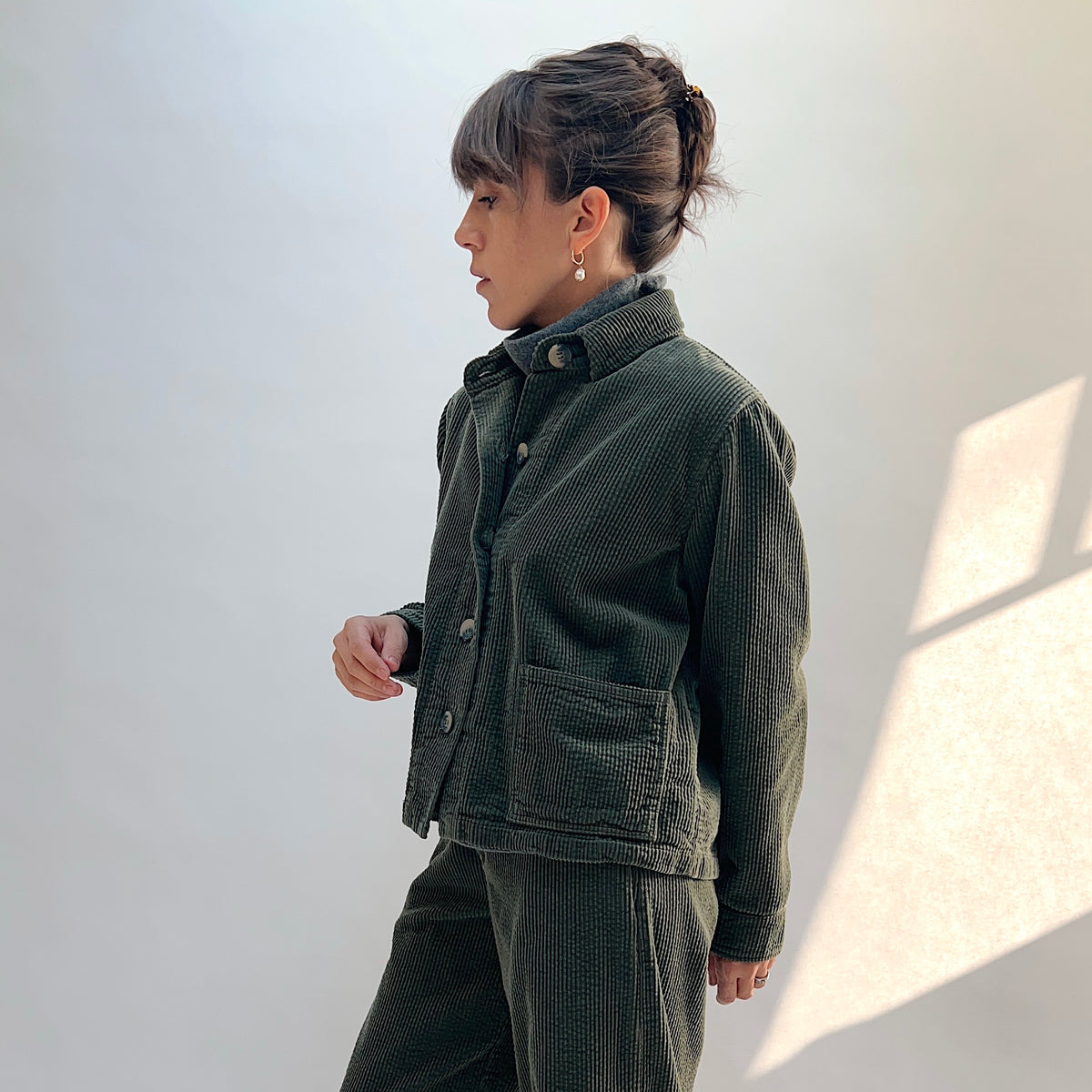 Side view of the Lux Corduroy Cropped Jacket in Kelp on a model, showing the long sleeves, corduroy texture, and cropped hem.
