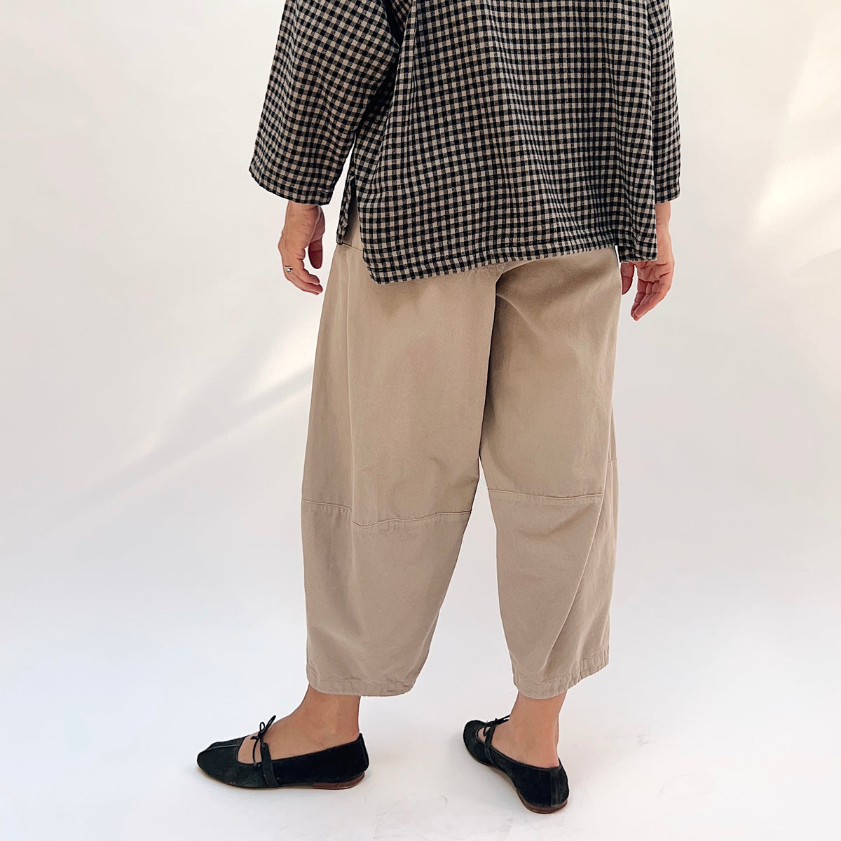 Eleven Stitch Corduroy Three Pocket Pant in Fennel, back view showing the relaxed balloon leg and elasticized ankle tapering, styled with a gingham check shirt

