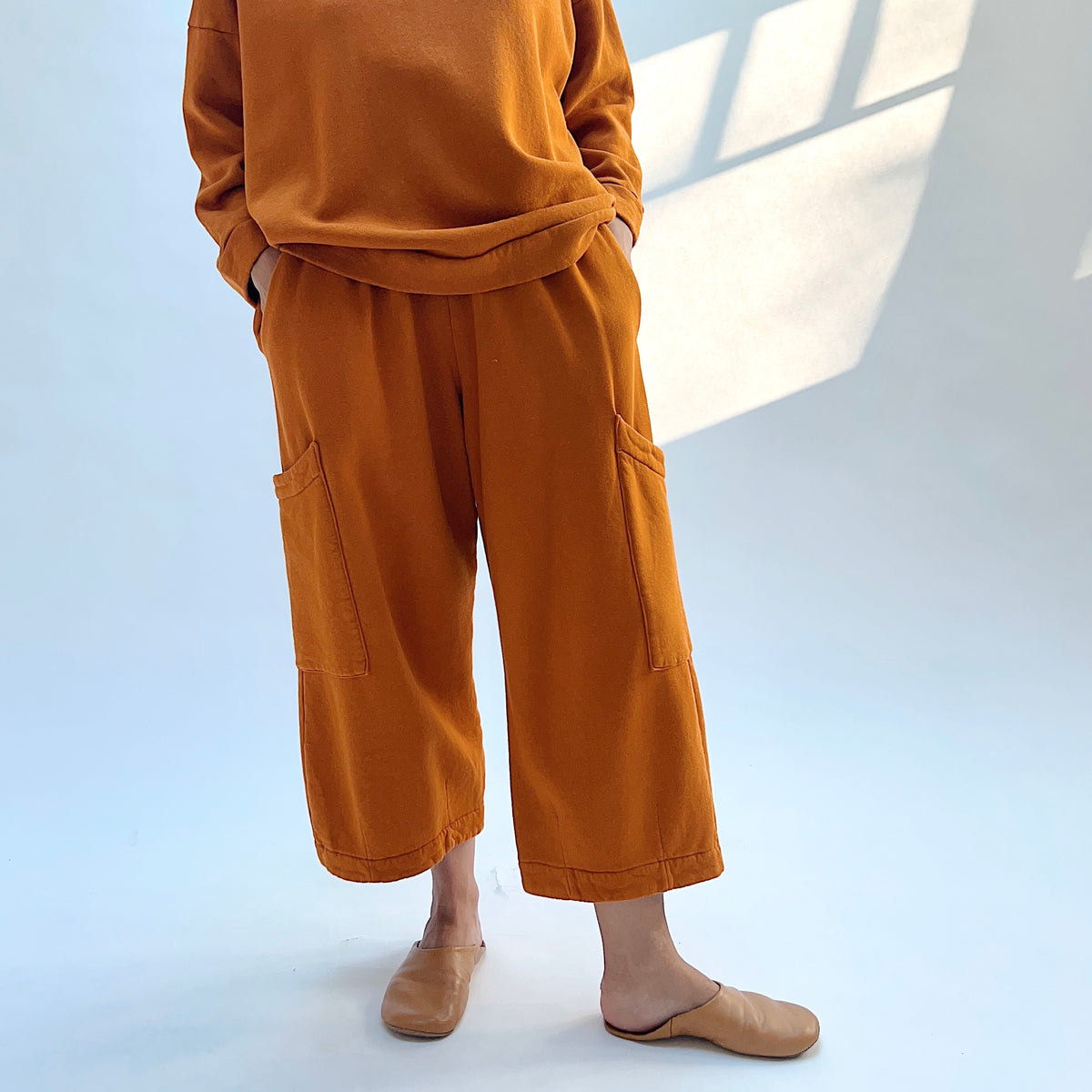 Model wearing Pasha Fleece Pant in Yera with hands in the side pockets, showing the wide legs and two thigh patch pockets.
