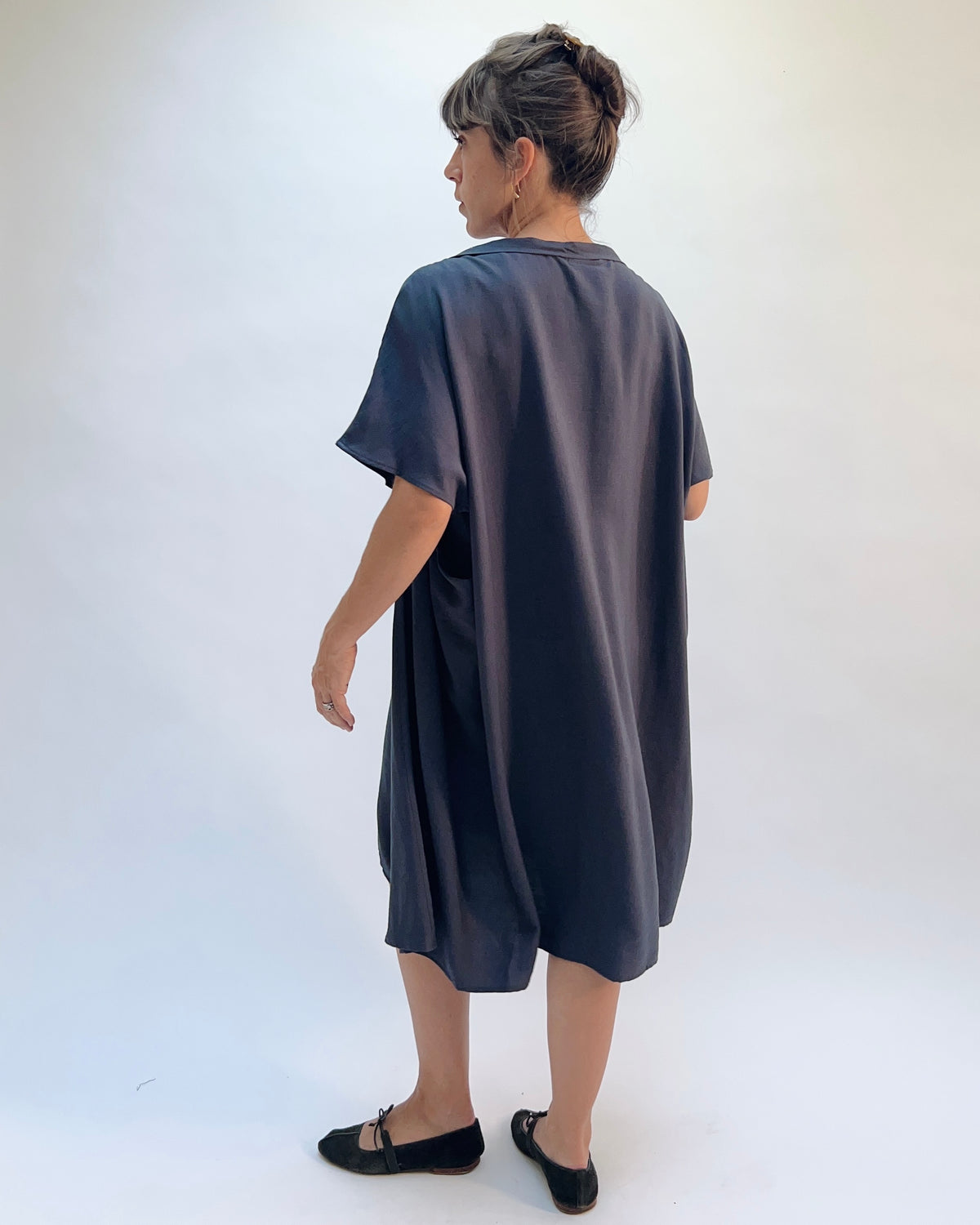 Niche Origami Dress in Carbon, back view showing the relaxed short-sleeve silhouette and flowy midi length in dark carbon rayon
