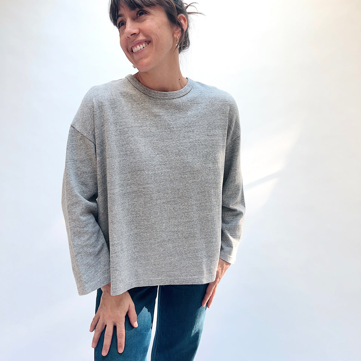 Front view of a model wearing the grey cotton knit pullover with a round neckline and dropped shoulders.
