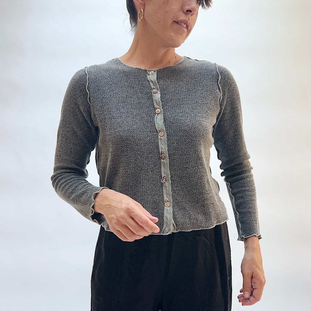Model wearing the Marled Knit Cropped Cardigan in Squirrel, front view, button-front cropped cardigan in heathered gray marled knit with contrast button placket and scalloped edges, styled with black trousers
