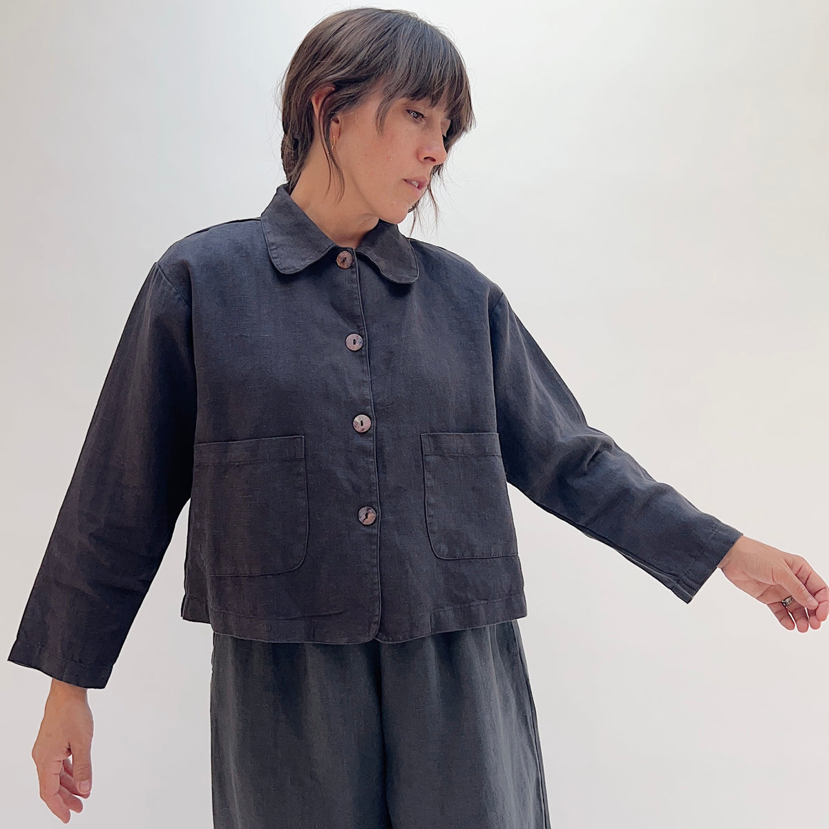 Model wearing the Bryn Walker Heavy Linen Audrey Jacket in Fig, front view, showing rounded collar, shell buttons, and patch pockets
