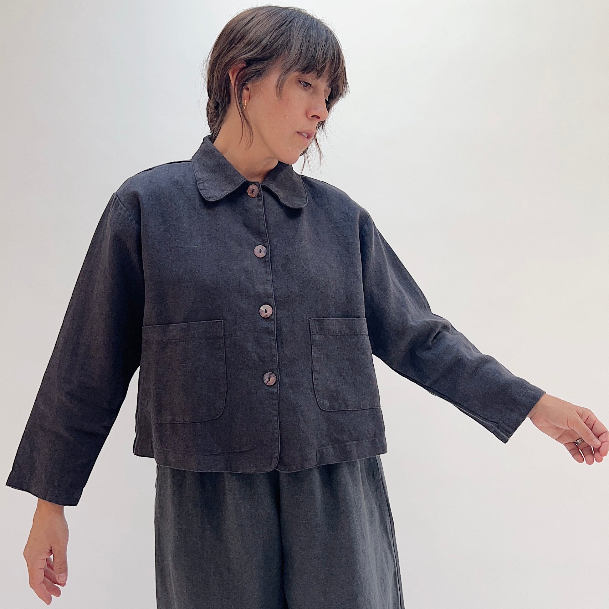Model wearing the Bryn Walker Heavy Linen Audrey Jacket in Fig, front view, showing rounded collar, shell buttons, and patch pockets
