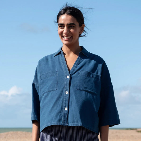 Woman wearing a blue shirt standing in a desert landscape with a clear blue sky.