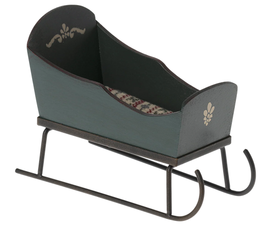Maileg miniature green sleigh with cream painted motifs, curved metal runners, and a patterned mattress.
