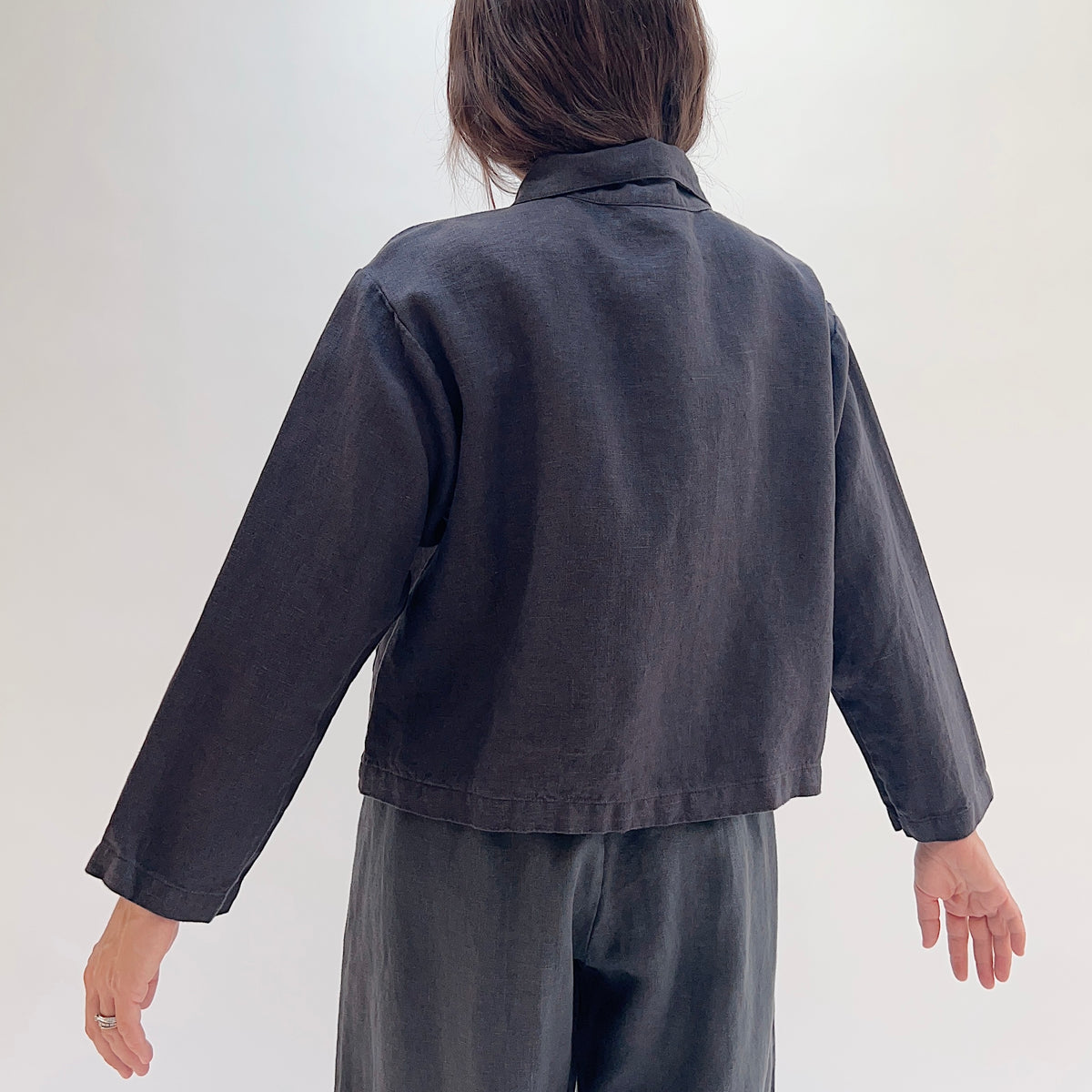Back view of the Bryn Walker Heavy Linen Audrey Jacket in Fig, showing cropped hemline and linen texture
