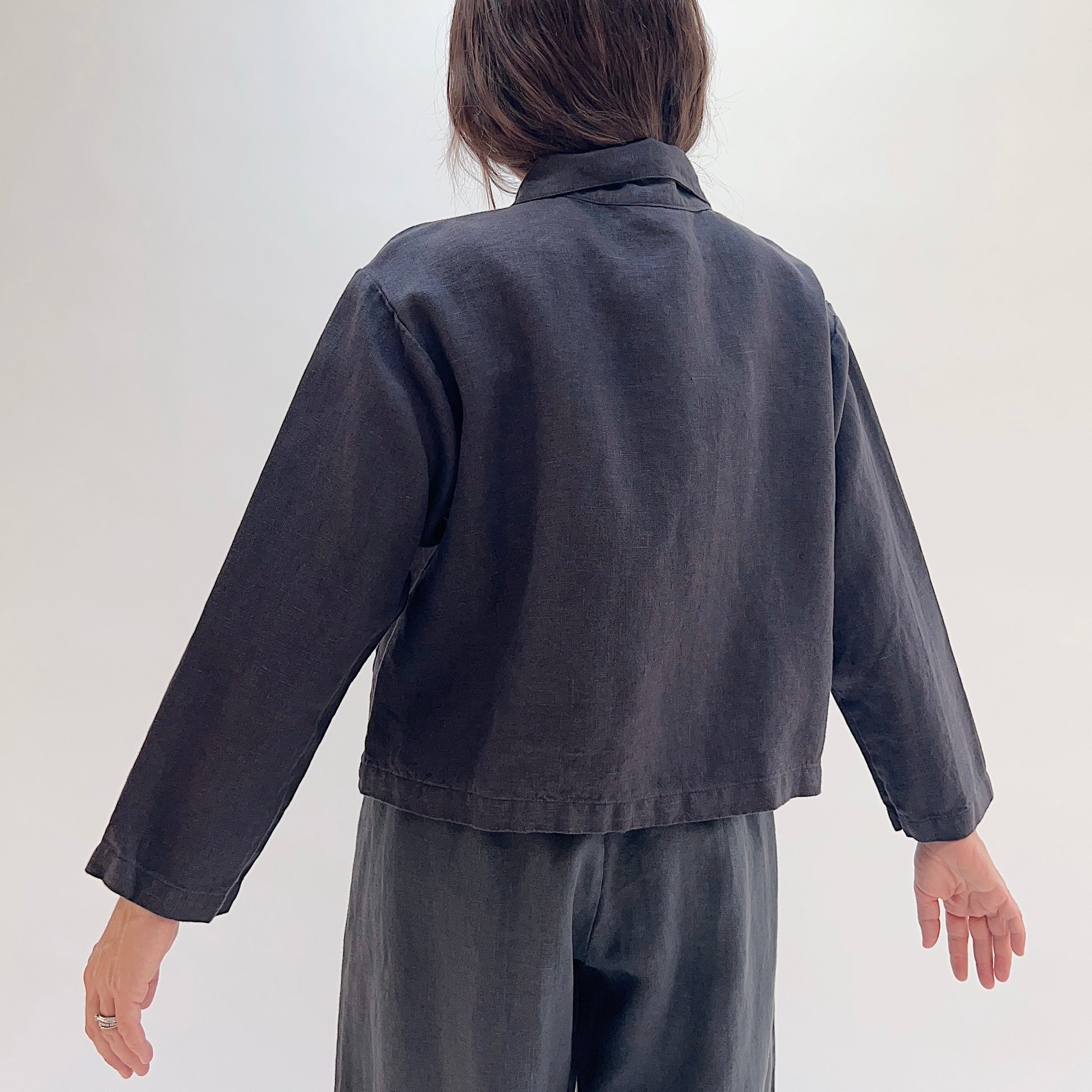 Back view of the Bryn Walker Heavy Linen Audrey Jacket in Fig, showing cropped hemline and linen texture
