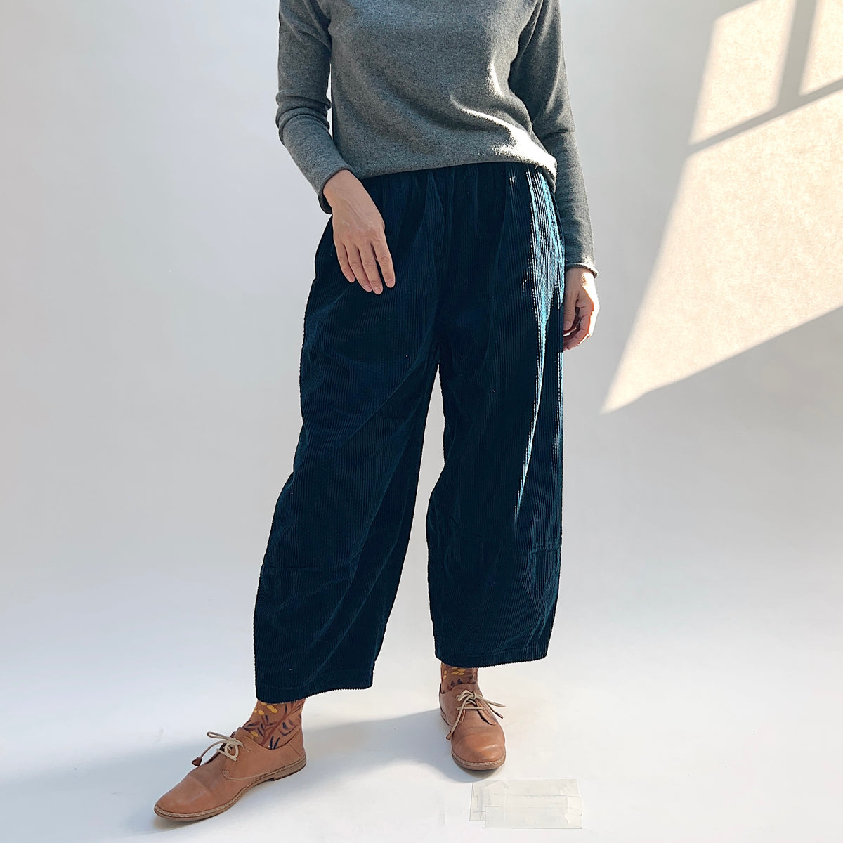 Front view of the Cut Loose Lux Corduroy Lantern Pant in Etan on a model, showing the dark teal corduroy and curved legs.
