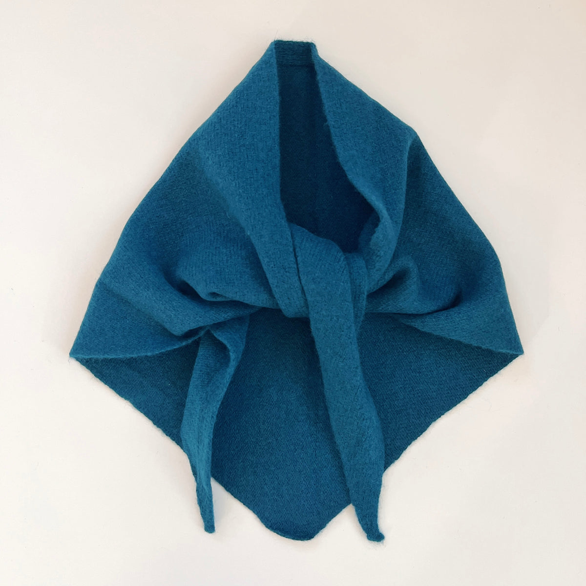 Ocean blue merino wool triangle scarf arranged flat with a loose knot and pointed ends.
