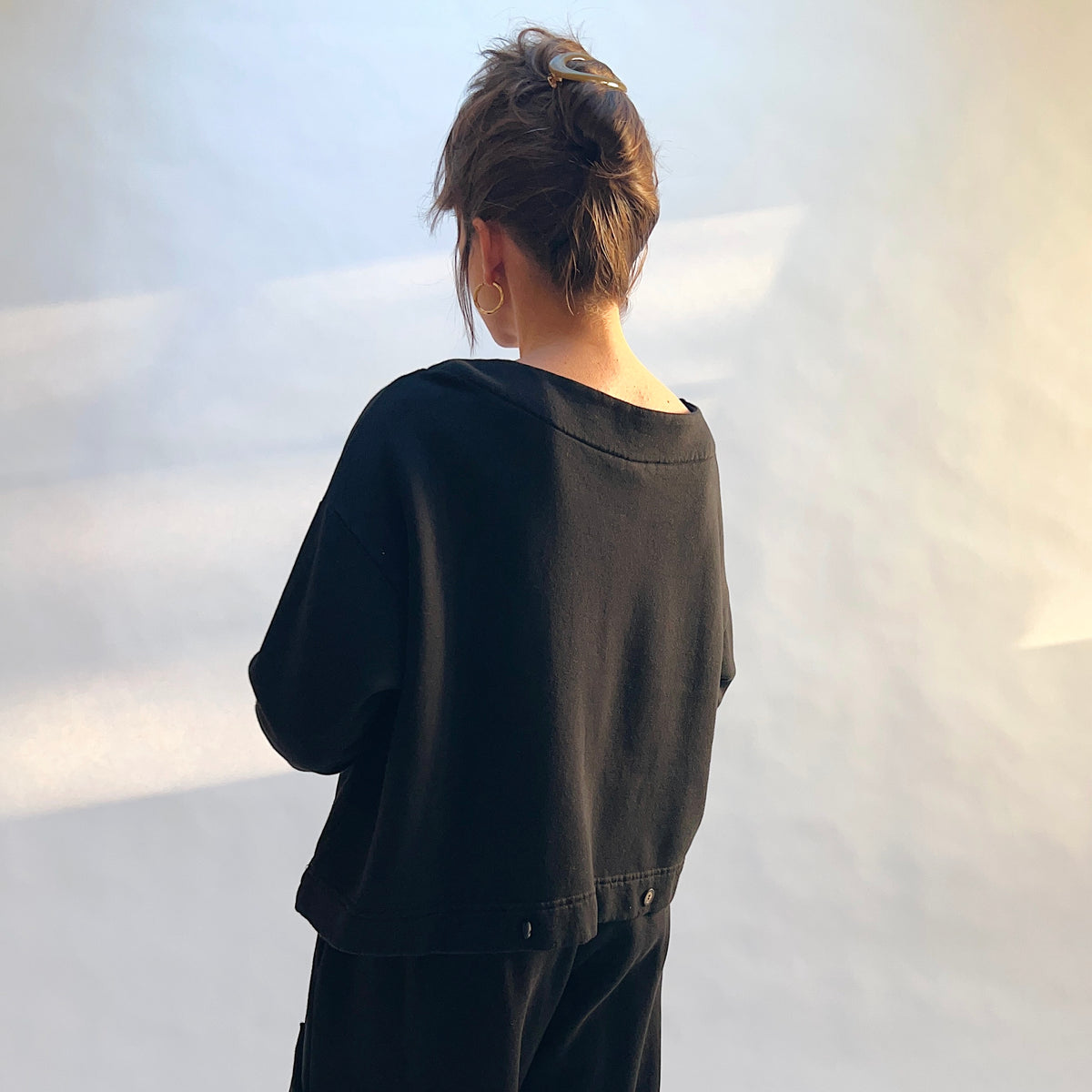 Angled back view of Button Back Fleece Pullover in Black, showing the button details along the lower hem.
