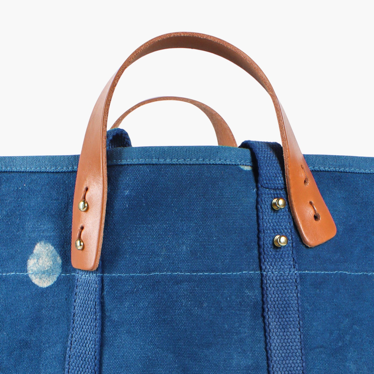 Close-up of the Small Light Indigo Moon tote’s leather handles, metal buttons, and blue canvas.
