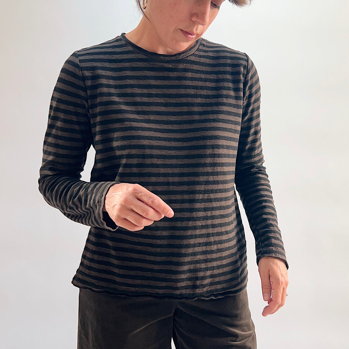 Model wearing the Cut Loose Striped Long Sleeve Easy Tee in Chocolate from the front, showing the relaxed crew neckline, long sleeves, and slightly curved hem in a lightweight chocolate and black horizontal stripe cotton-linen blend, paired with the chocolate wide-leg crop trouser
