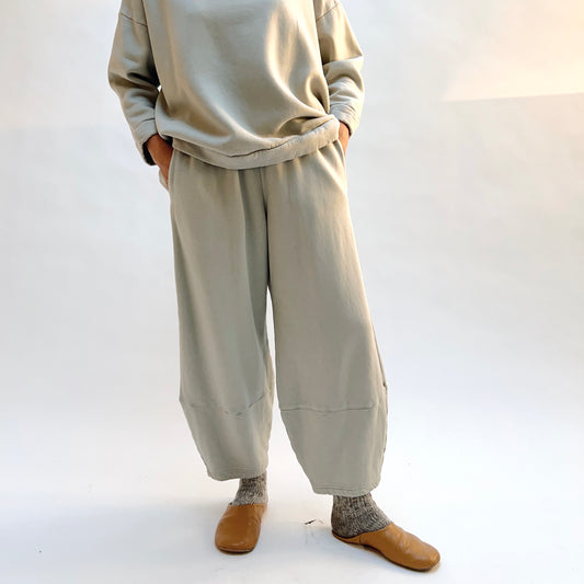 Front view of Bryn Walker Oliver Fleece Pant in Orlaya on a model with hands in the side pockets, showing the rounded legs and lower-leg seams.
