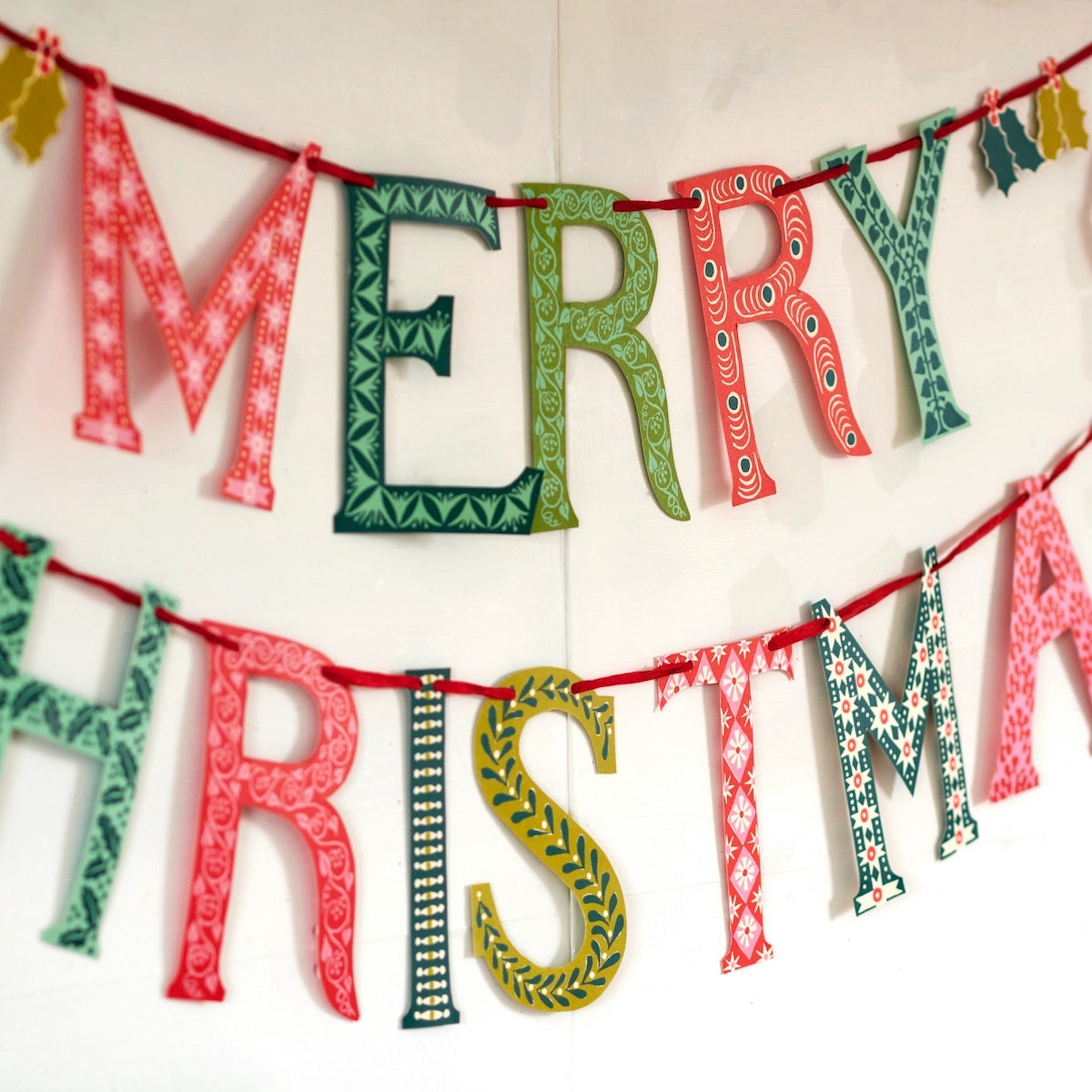 Decorative Christmas banner with patterned letters spelling 'Merry Christmas' on a white background.