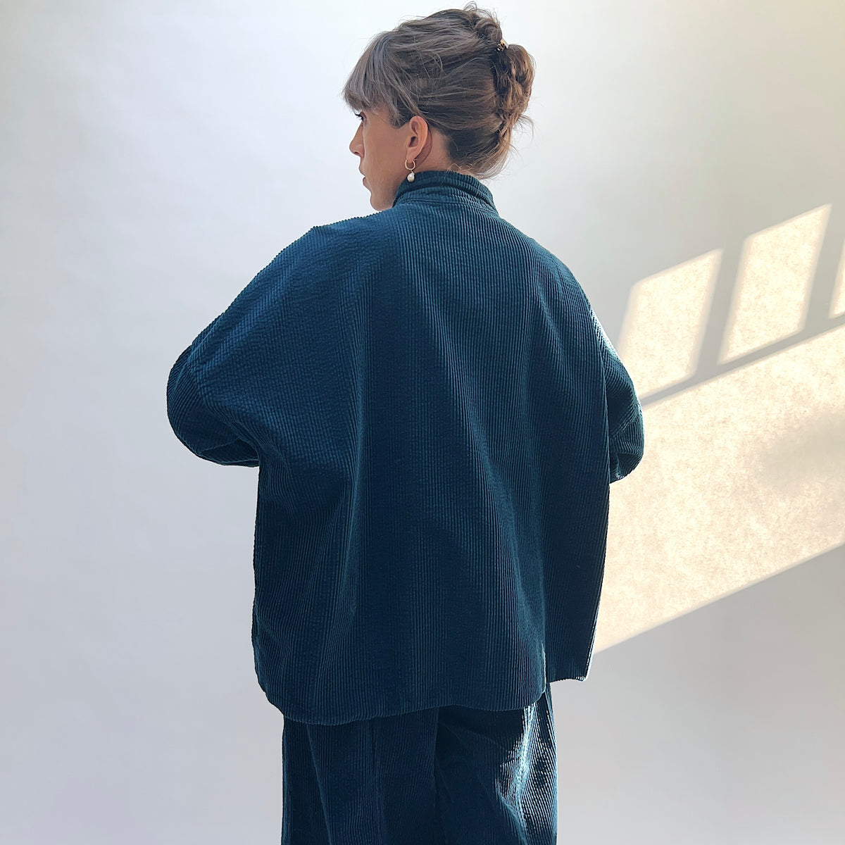 Back view of the Lux Corduroy Oversized Shirt in Etan on a model, showing the vertical corduroy texture and curved hem.
