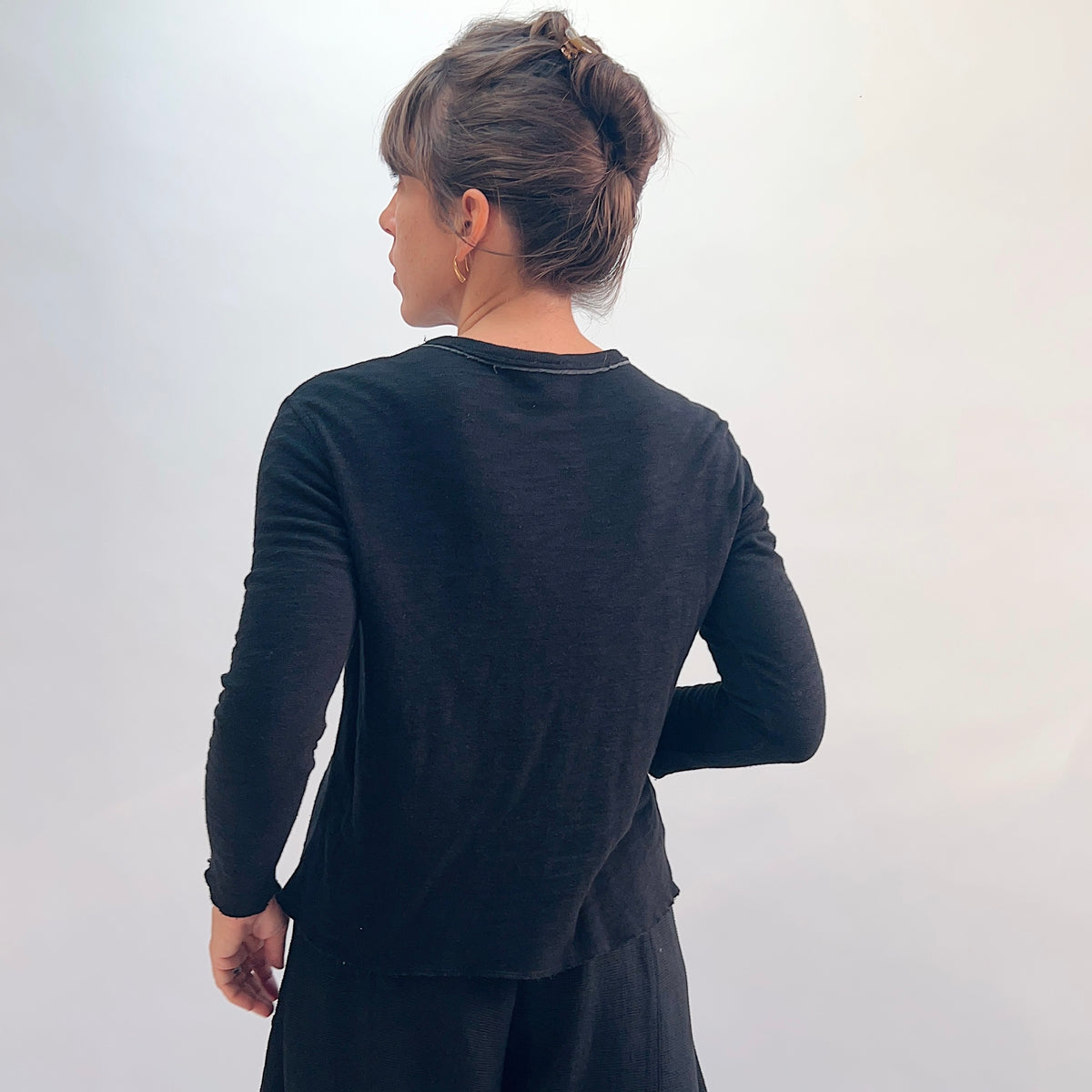 North Star Base Double Cotton Tee in Black, back view showing the slightly cropped double-layered long-sleeve silhouette with exposed raw-edge neckline seam detail
