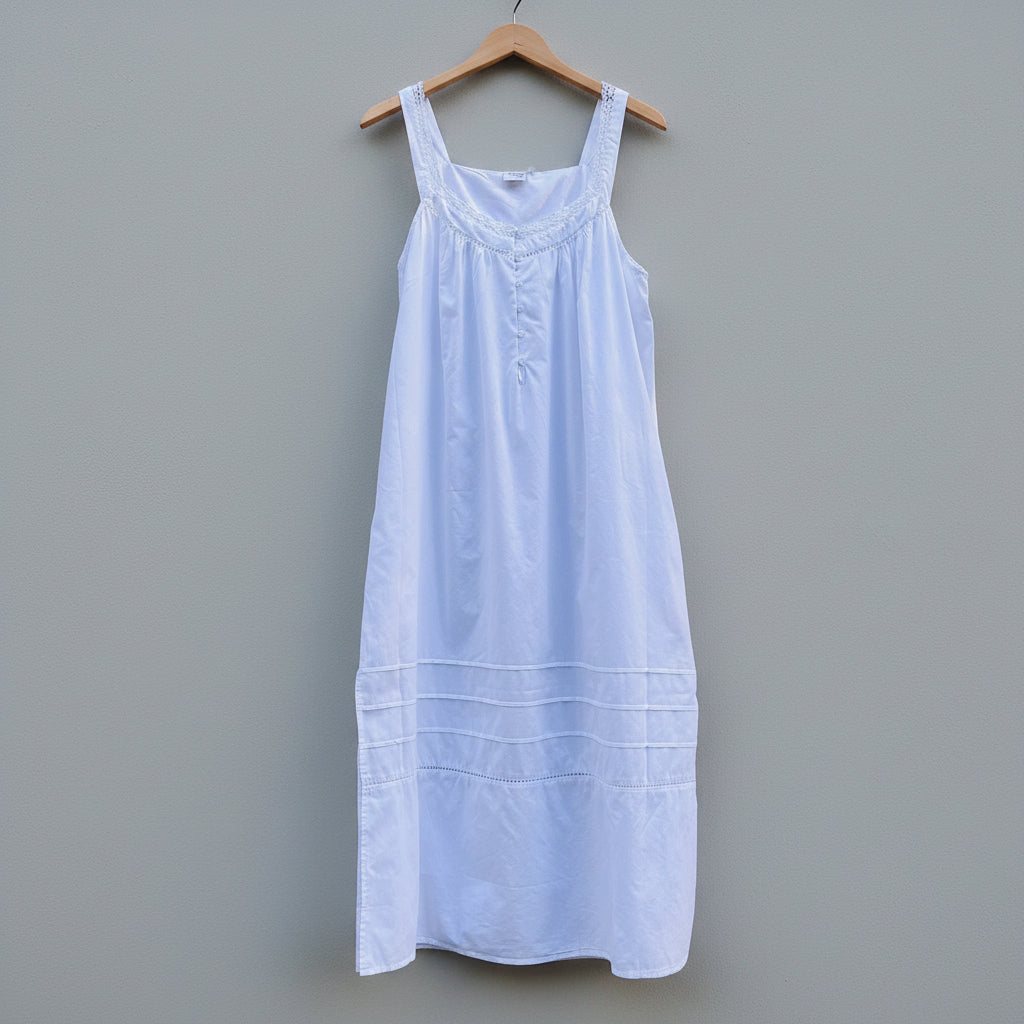White dress on a wooden hanger against a gray concrete wall