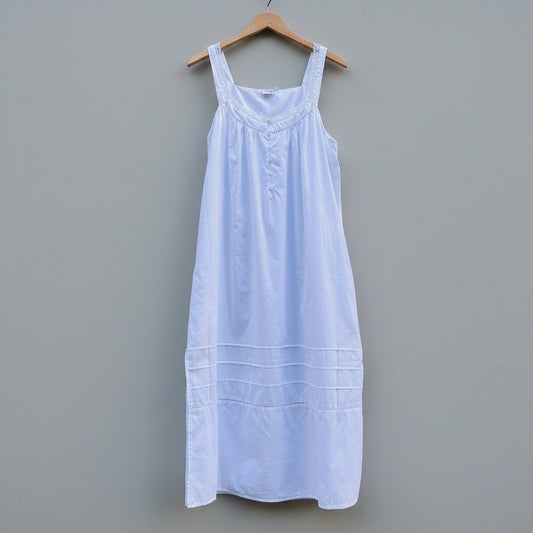 White dress on a wooden hanger against a gray concrete wall
