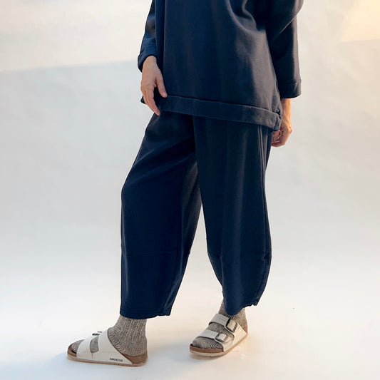 Angled front view of Bryn Walker Oliver Fleece Pant in Nova on a model, showing the rounded legs tapering toward the ankles.
