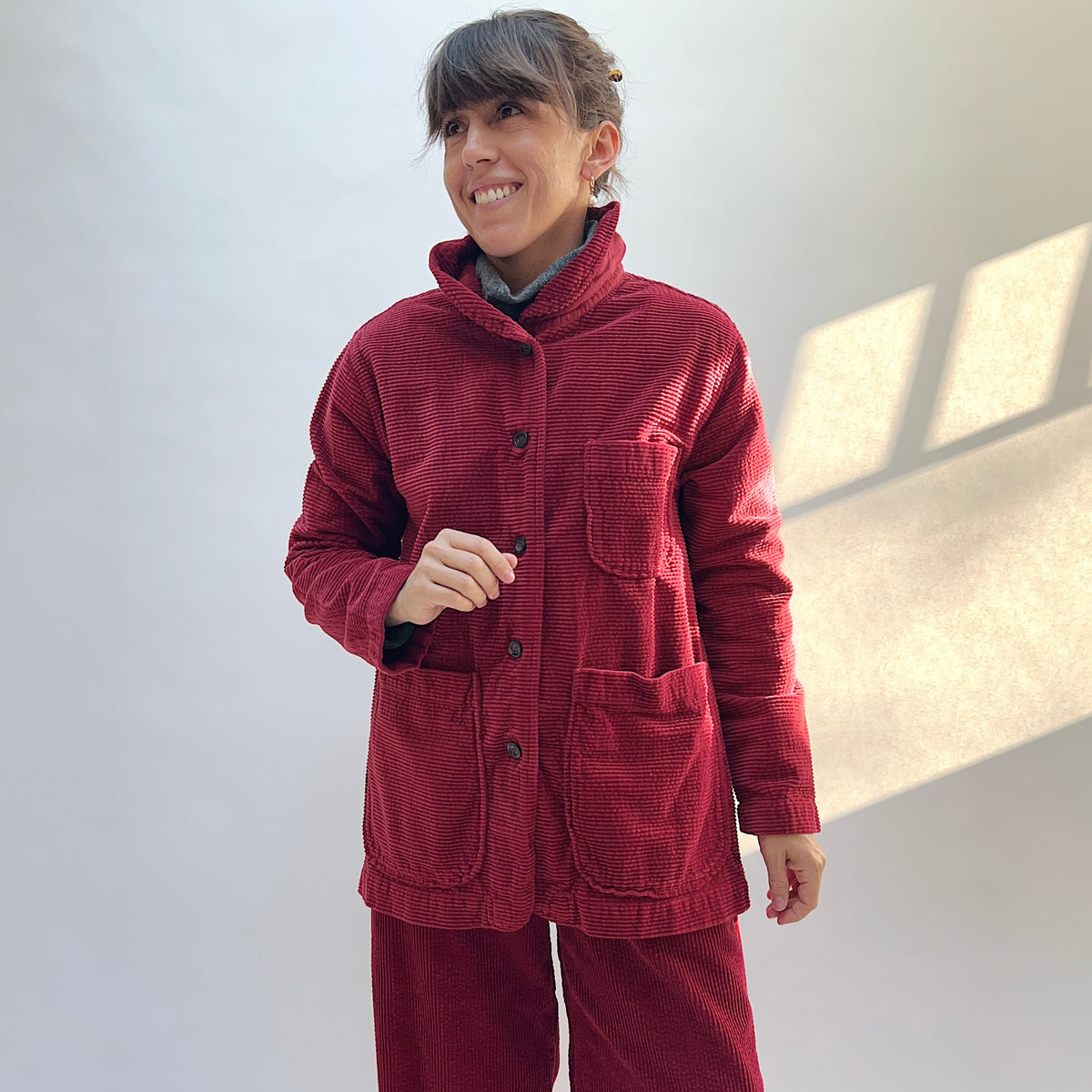 Front view of the Cut Loose Lux Corduroy Long Blazer in Maraschino on a model, showing the raised collar, button front, and patch pockets.

