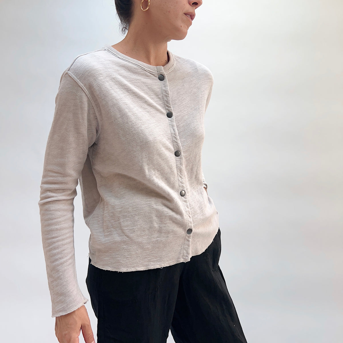 Model wearing the Cut Loose Snap Front Cardigan in Nimbus, three-quarter side view, showing snap button placket and relaxed fit in light heathered gray cotton
