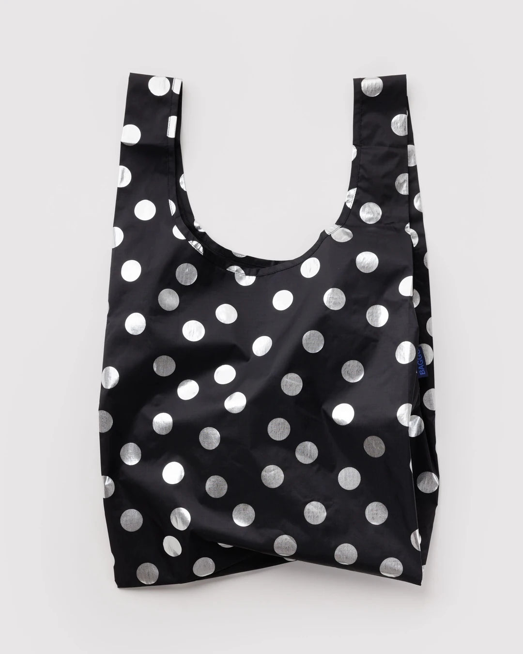 BAGGU Standard Baggu in Silver Metallic Polka Dot, shown unfolded with two handles and shiny silver dots on black fabric.
