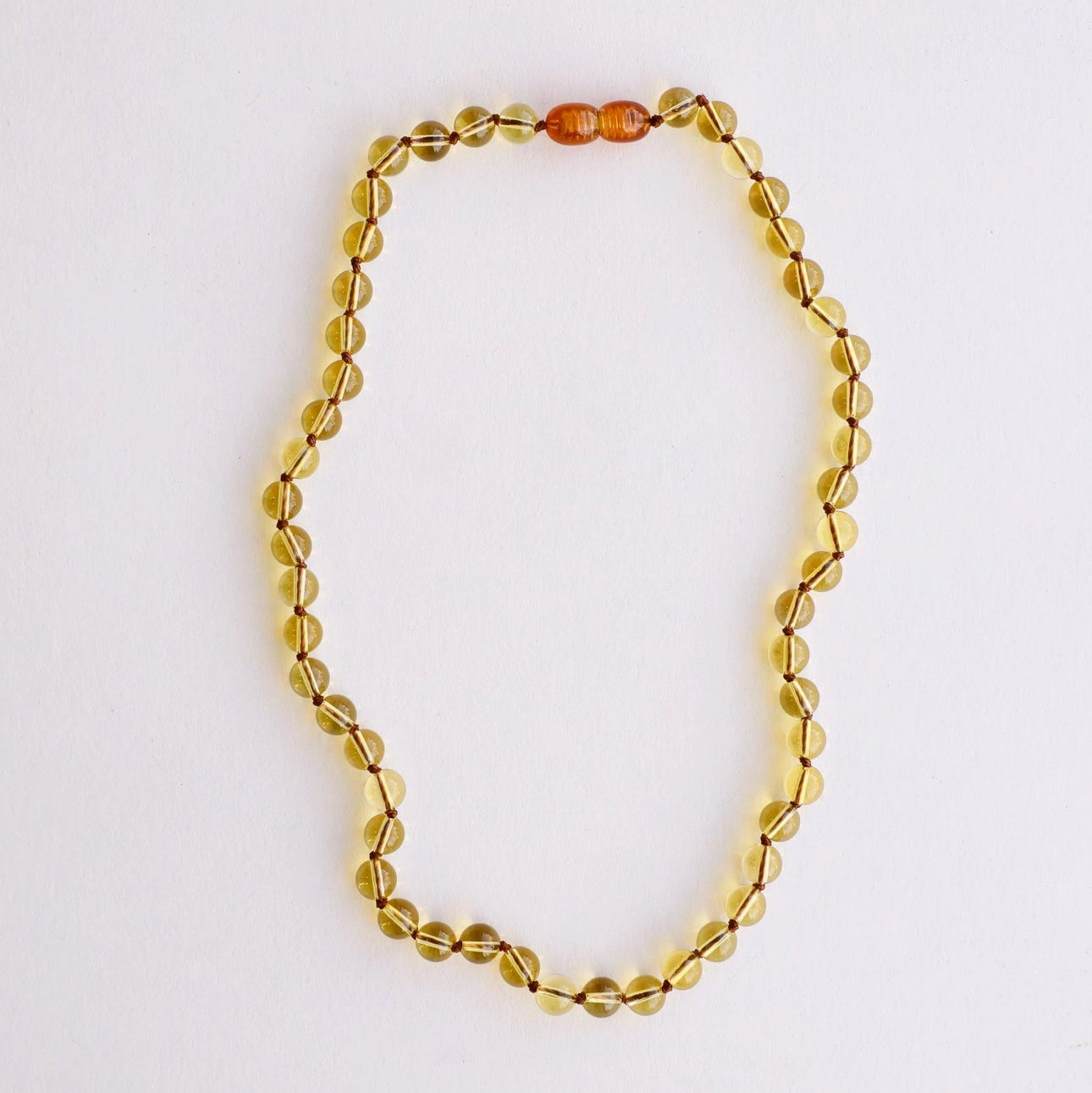 CanyonLeaf Pure Gemstone + Citrine Necklace — a hand-knotted necklace of smooth translucent pale yellow citrine beads with a honey amber screw clasp, laid flat on a white background