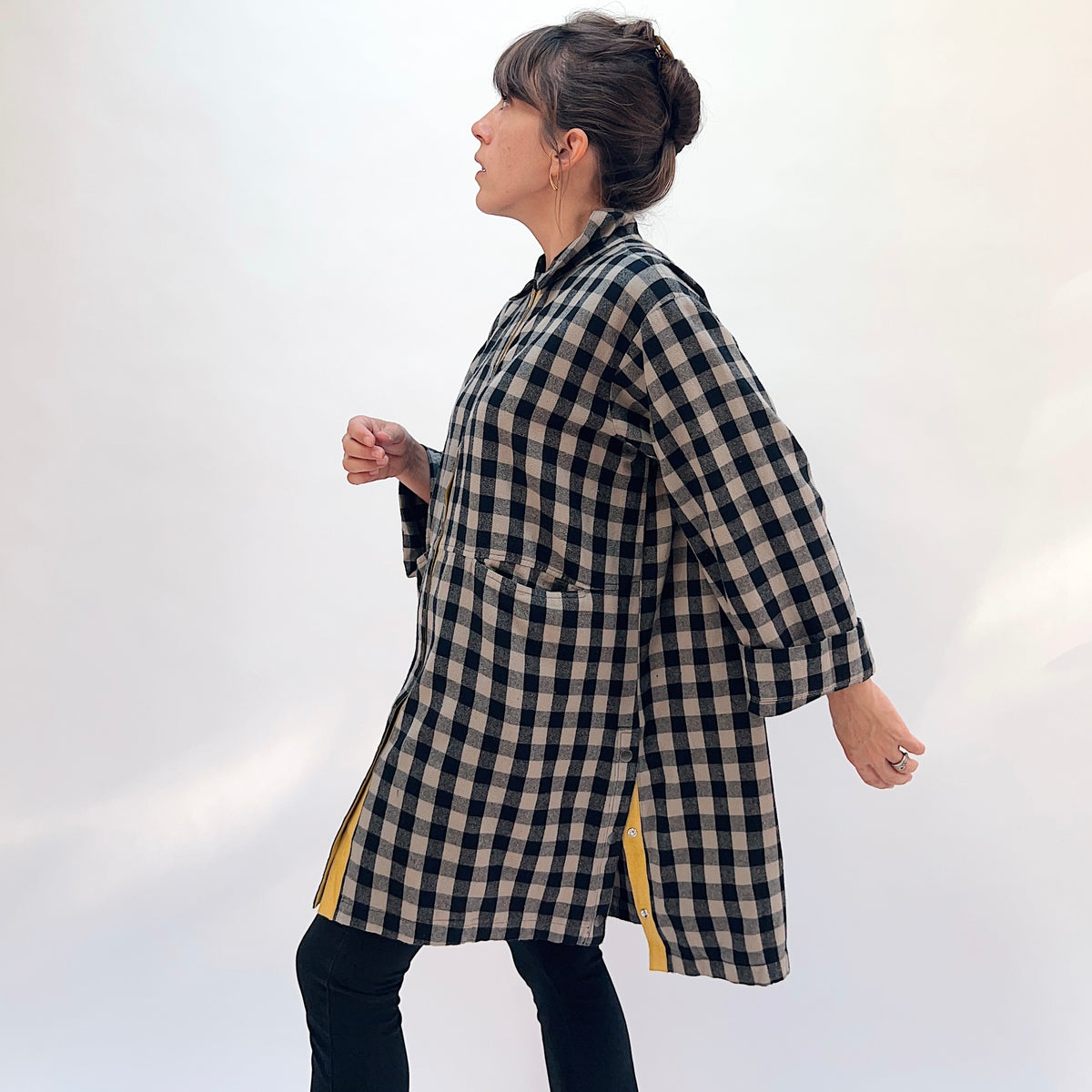 Eleven Stitch Duster in Fennel, side view showing the oversized fit, point collar, button-front with mustard contrast placket, and two large hip patch pockets in black and natural gingham check flannel
