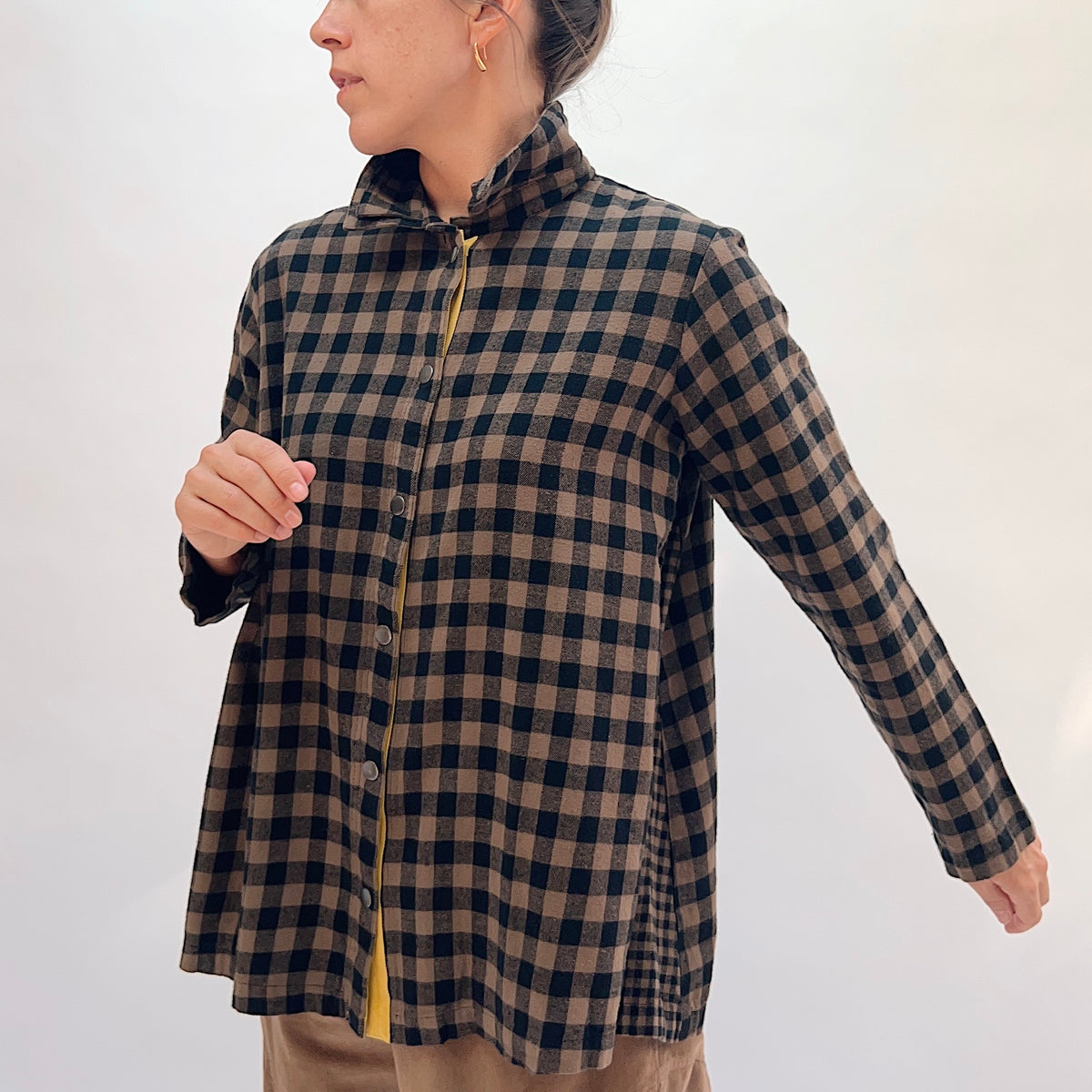 Eleven Stitch Placket Gusset Shirt in Winter Olive, three-quarter front view showing the brown and black gingham check, high funnel collar, button-front placket with yellow contrast detail, and side gusset snap vent
