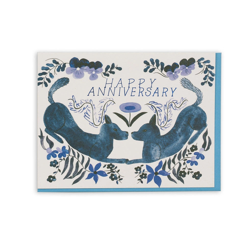 Small Adventure Anniversary Folk Dogs Card, two blue dogs facing each other among flowers and leaves beneath the words “Happy Anniversary,” shown with a blue envelope.

