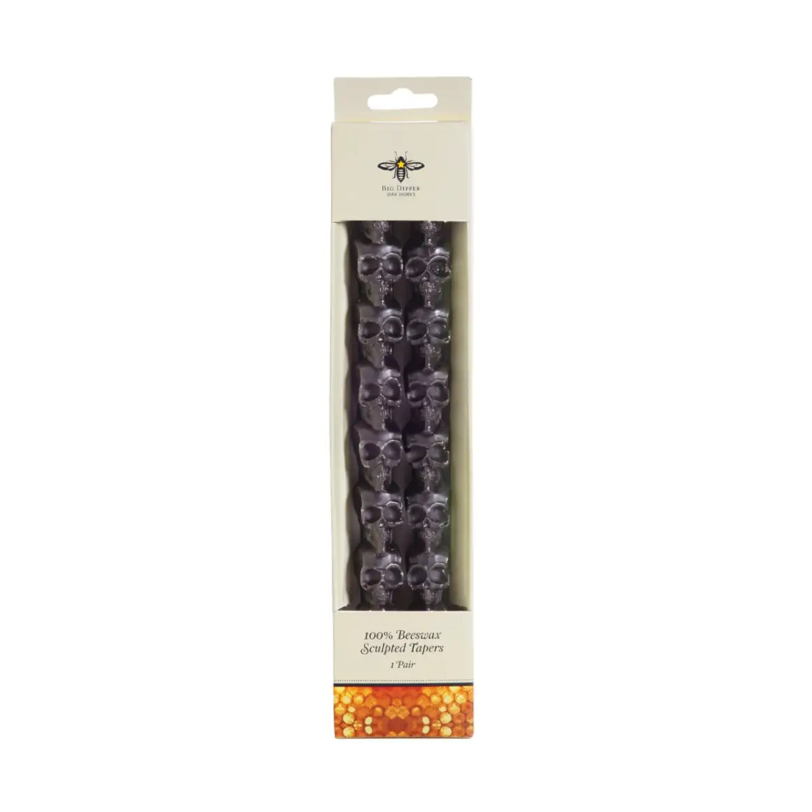 Big Dipper Wax Works 10-inch Sculpted Black Skull Tapers in retail packaging, front view against a white background, showing two dark charcoal beeswax taper candles with a stacked skull silhouette shape inside a white windowed box labeled 100% Beeswax Sculpted Tapers, 1 Pair, with a Big Dipper Wax Works logo at the top and a honeycomb pattern at the base
