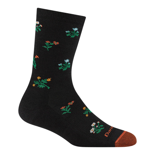 Darn Tough black crew sock with small multicolored wildflowers, green stems and leaves, and a rust-orange toe.
